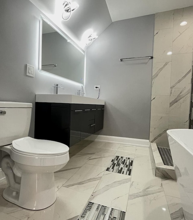 bathroom featuring vanity, a tub to relax in, and toilet