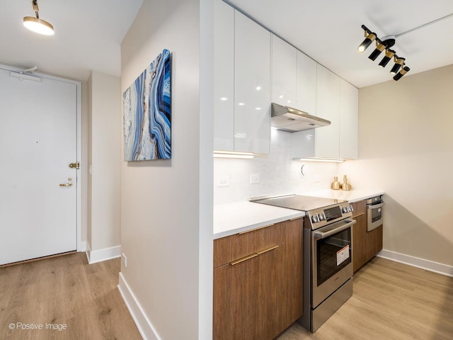 kitchen featuring white cabinetry, backsplash, appliances with stainless steel finishes, and light hardwood / wood-style flooring