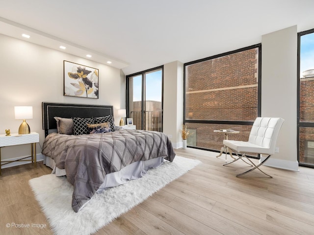 bedroom with a wall of windows and light hardwood / wood-style flooring