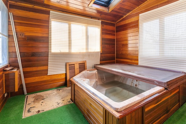 interior space featuring a wealth of natural light, lofted ceiling with skylight, wood walls, and dark colored carpet