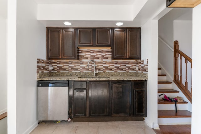 kitchen featuring dishwasher, light stone counters, dark brown cabinetry, and sink