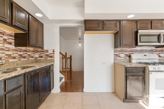 kitchen featuring backsplash, dark brown cabinetry, light tile patterned floors, and white range with gas stovetop