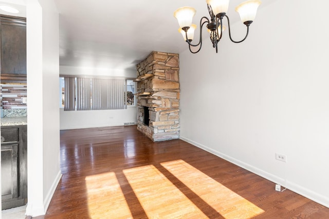 unfurnished living room featuring hardwood / wood-style flooring, a fireplace, and an inviting chandelier