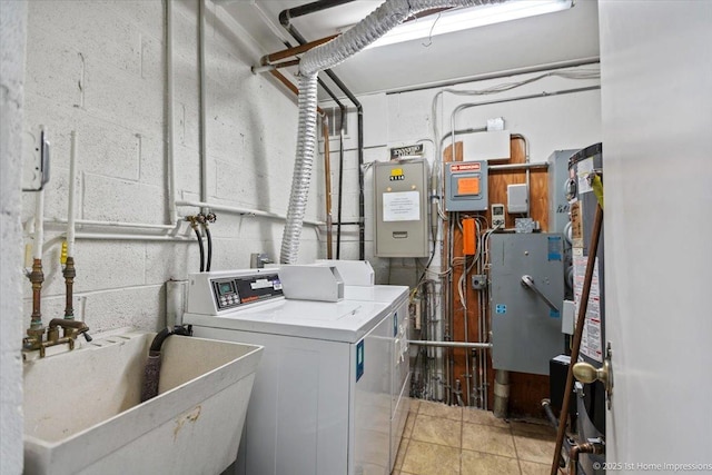 clothes washing area featuring light tile patterned flooring, independent washer and dryer, and sink