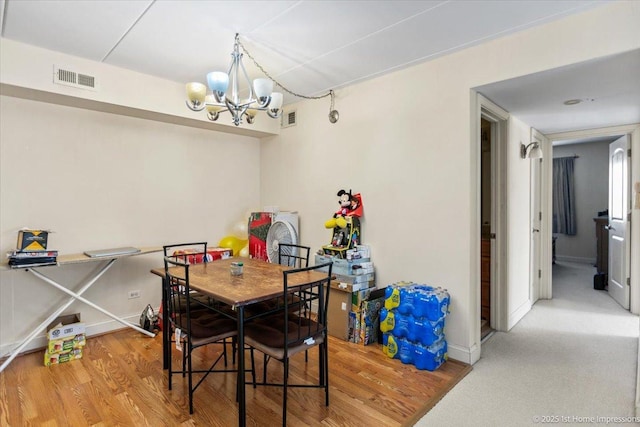 dining area with wood-type flooring and an inviting chandelier