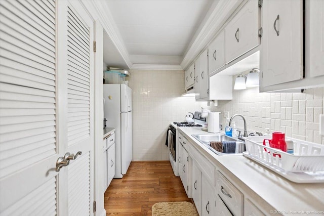 kitchen featuring white appliances, backsplash, white cabinets, sink, and dark hardwood / wood-style floors