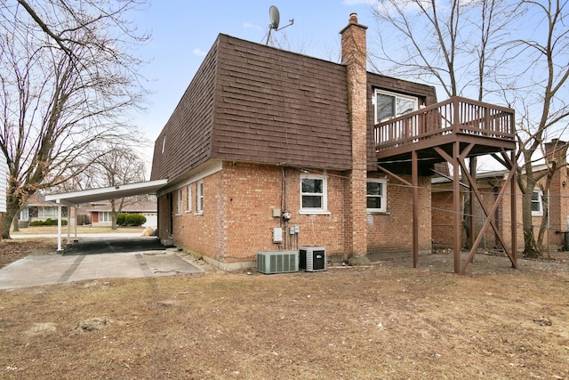 rear view of house with central air condition unit, a deck, and a carport