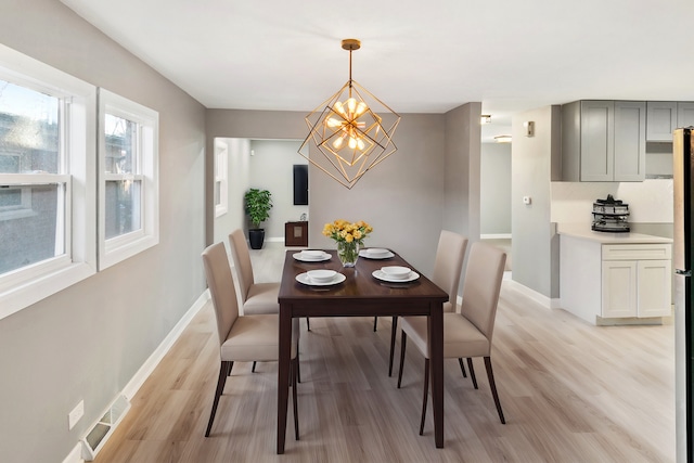 dining space featuring light wood-type flooring and an inviting chandelier