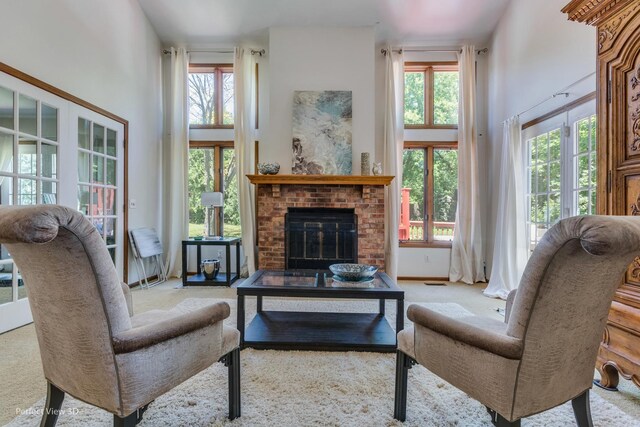 carpeted living room with a towering ceiling and a brick fireplace