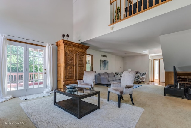 carpeted living room featuring a towering ceiling