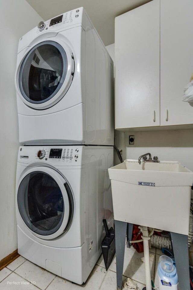 washroom featuring cabinets, stacked washer and dryer, light tile patterned flooring, and sink