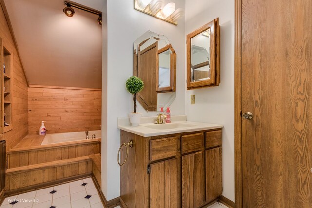 bathroom featuring tile patterned flooring, vanity, a tub, and vaulted ceiling