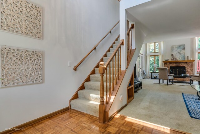 stairway featuring parquet floors, a fireplace, and a towering ceiling