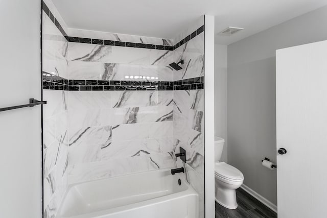 bathroom with toilet, tiled shower / bath, and wood-type flooring