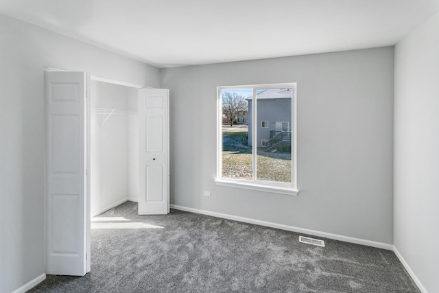 unfurnished bedroom featuring multiple windows, a closet, and dark colored carpet