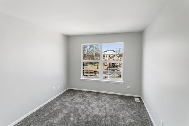 spare room featuring dark carpet