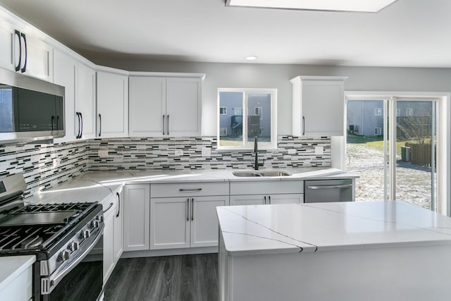 kitchen featuring sink, light stone counters, white cabinetry, and stainless steel appliances