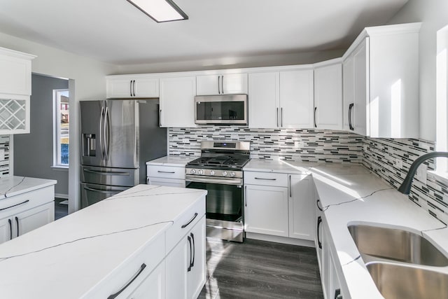 kitchen featuring appliances with stainless steel finishes, decorative backsplash, light stone countertops, white cabinets, and sink