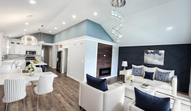 living room with high vaulted ceiling, a fireplace, hardwood / wood-style floors, and a notable chandelier