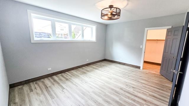 unfurnished bedroom with a walk in closet, a closet, and light hardwood / wood-style flooring