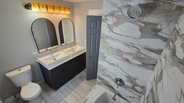 full bathroom featuring shower / washtub combination, vanity, and toilet