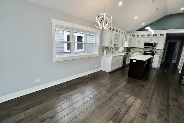 kitchen featuring appliances with stainless steel finishes, hanging light fixtures, a center island, white cabinetry, and tasteful backsplash