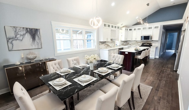 dining room with vaulted ceiling and dark wood-type flooring