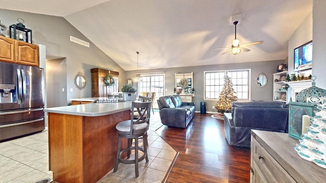 kitchen featuring hardwood / wood-style floors, a center island, lofted ceiling, ceiling fan, and stainless steel fridge with ice dispenser