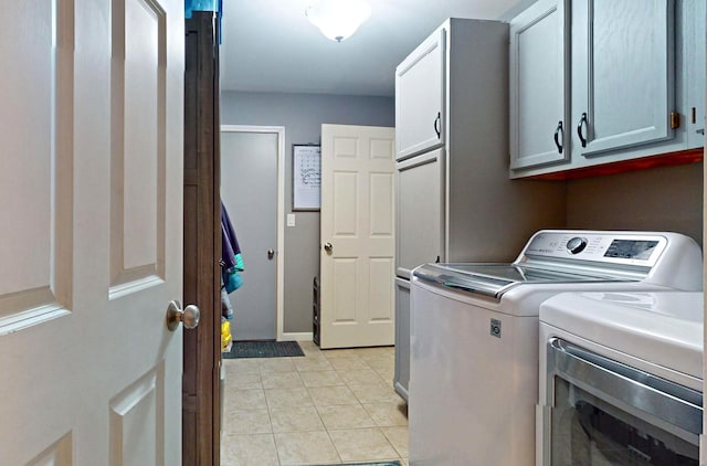 clothes washing area with cabinets, light tile patterned floors, and separate washer and dryer