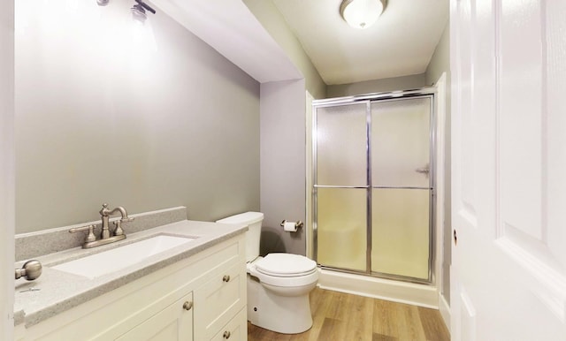 bathroom featuring wood-type flooring, vanity, toilet, and walk in shower