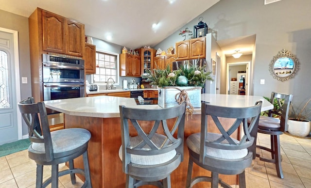 kitchen with dishwasher, a center island, stainless steel double oven, lofted ceiling, and light tile patterned floors