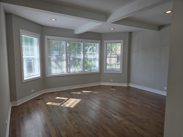 spare room featuring beam ceiling, a wealth of natural light, and dark wood-type flooring