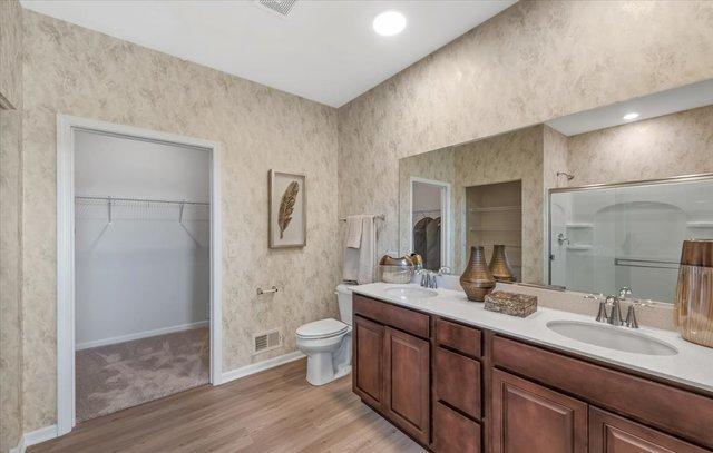 bathroom with hardwood / wood-style floors, vanity, toilet, and a shower with shower door