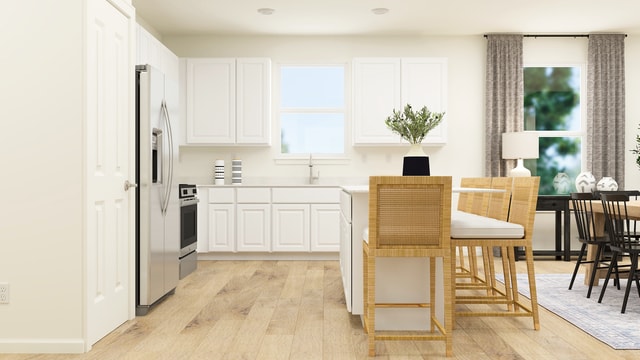 kitchen featuring stove, sink, light hardwood / wood-style flooring, stainless steel fridge, and white cabinetry