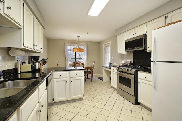 kitchen featuring pendant lighting, backsplash, kitchen peninsula, appliances with stainless steel finishes, and white cabinetry