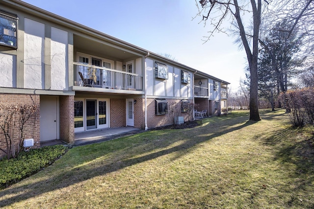 rear view of property with a yard, a patio area, a balcony, and central AC unit