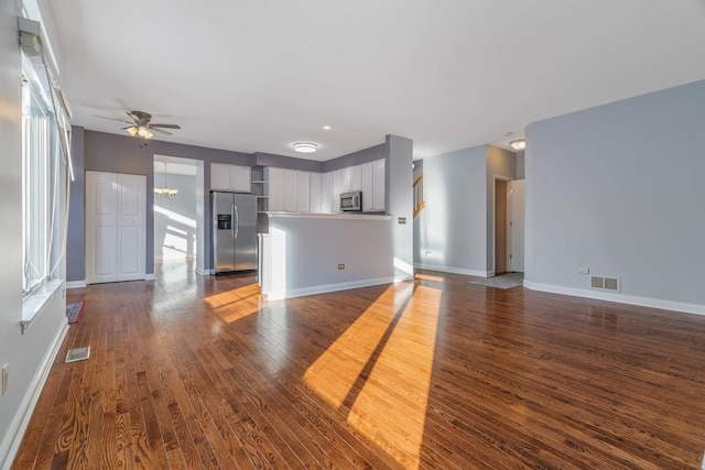 unfurnished living room featuring hardwood / wood-style flooring and ceiling fan with notable chandelier