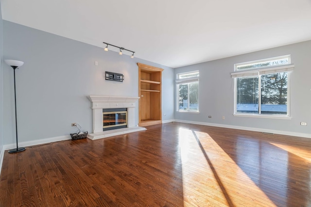 unfurnished living room featuring hardwood / wood-style flooring and rail lighting