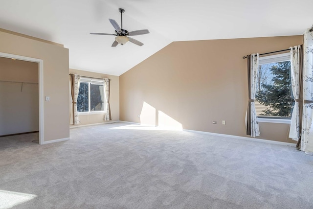 unfurnished bedroom with lofted ceiling, a walk in closet, light colored carpet, ceiling fan, and a closet