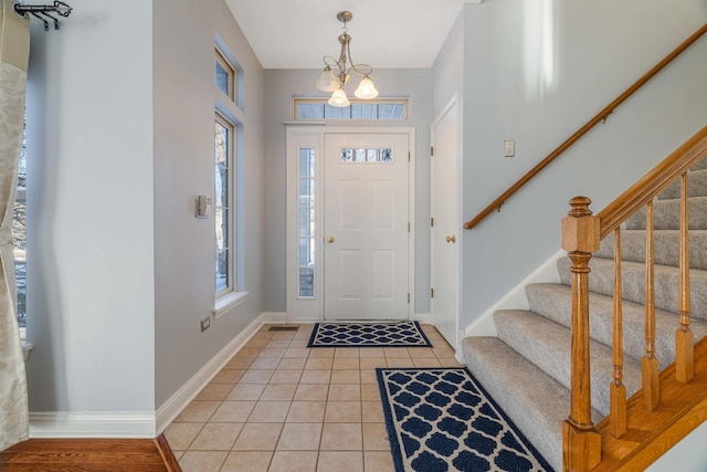 tiled entryway with a notable chandelier