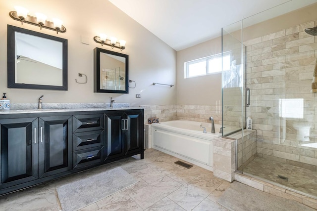 bathroom featuring vanity, vaulted ceiling, and independent shower and bath