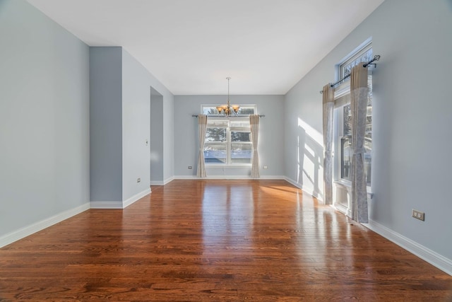 unfurnished dining area with dark hardwood / wood-style flooring, a notable chandelier, and a healthy amount of sunlight