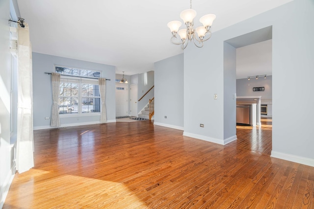 unfurnished living room with wood-type flooring and a chandelier