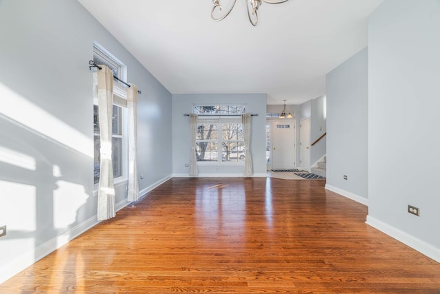 unfurnished living room with a chandelier and light hardwood / wood-style floors