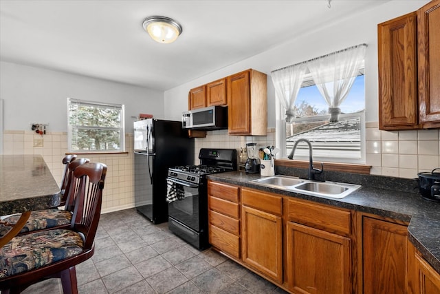 kitchen with light tile patterned floors, sink, a healthy amount of sunlight, and black appliances