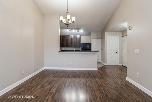 interior space featuring kitchen peninsula, dark hardwood / wood-style flooring, black fridge, dark brown cabinets, and a chandelier