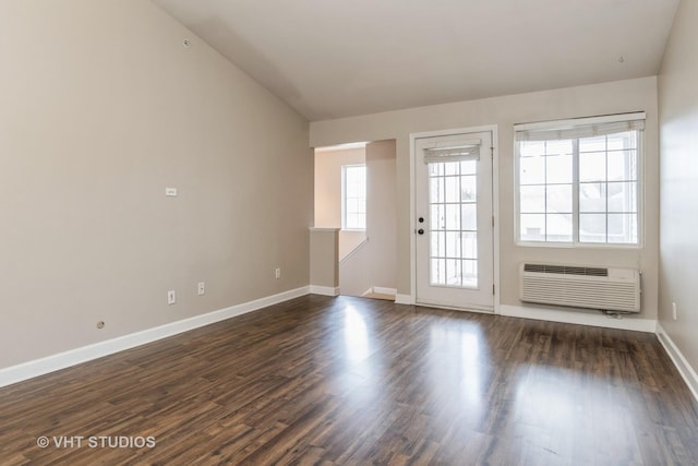 empty room featuring an AC wall unit and dark hardwood / wood-style flooring