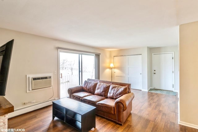 living room featuring dark hardwood / wood-style flooring, baseboard heating, and a wall unit AC