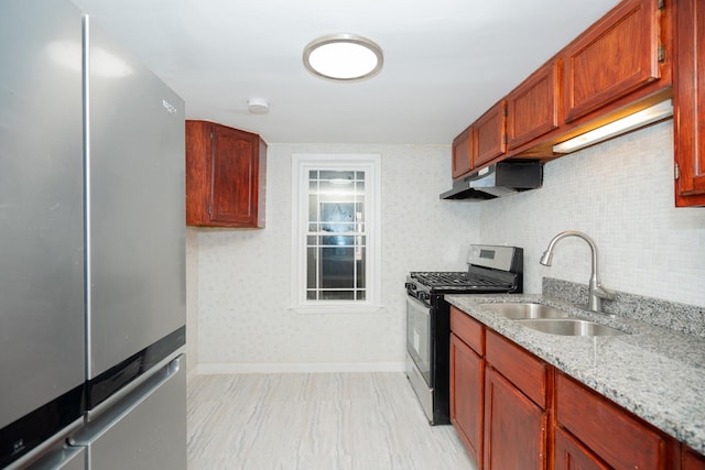 kitchen featuring decorative backsplash, light stone counters, sink, and appliances with stainless steel finishes