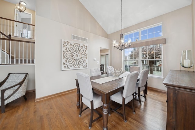 dining area featuring high vaulted ceiling, hardwood / wood-style floors, and a notable chandelier